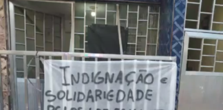 Faixa amarrada em portão com os dizeres: Indignação e solidariedade pelos mais de 50 mil mortos. Estado Assassino!